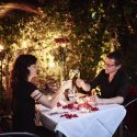 Zwei Gäste stossen bei Kerzenlicht im Garten des Restaurant Haberbüni mit Weingläsern an